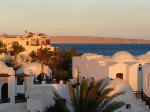 Vista panorámica de Hurghada en la riviera egipcia con tejados blancos y palmeras en primer plan y el Mar Rojo al fondo