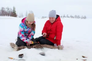 Pareja practicando pesca en el hielo durante viaje a Laponia