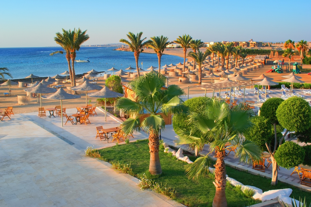 Vistal desde arriba de playa privada del Golden Beach Resort en Hurghada, con numerosas palmeras dando sobra a las amacas frente al azul cristalino del mar rojo