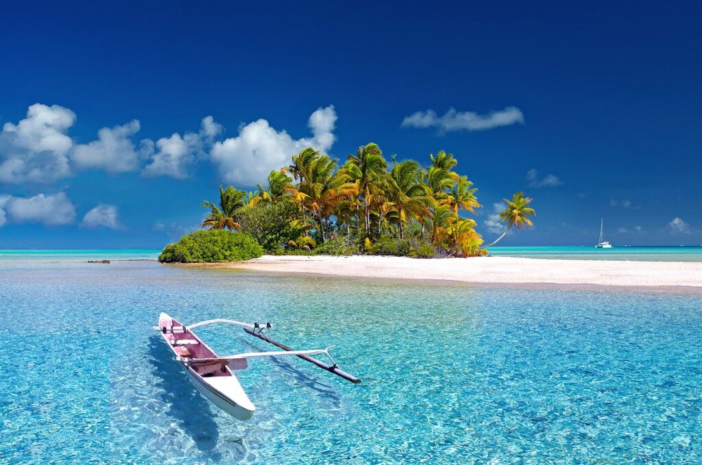 Canoa para novios en viaje de novios frente atolón en Polinesia con yate al fono y aguas cristalinas en primer plano. Ideal para viajes de novios 2024