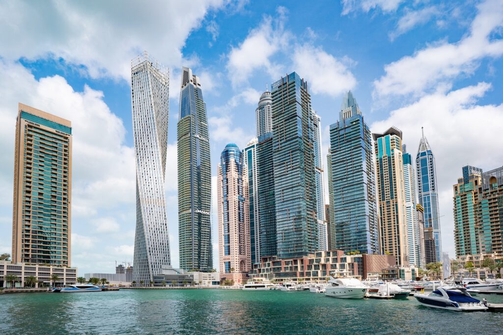 Vista panorámica del Cayan Tower y otros rascacielos de Dubai Marina tomada desde el agua con yates atracados en primer plano