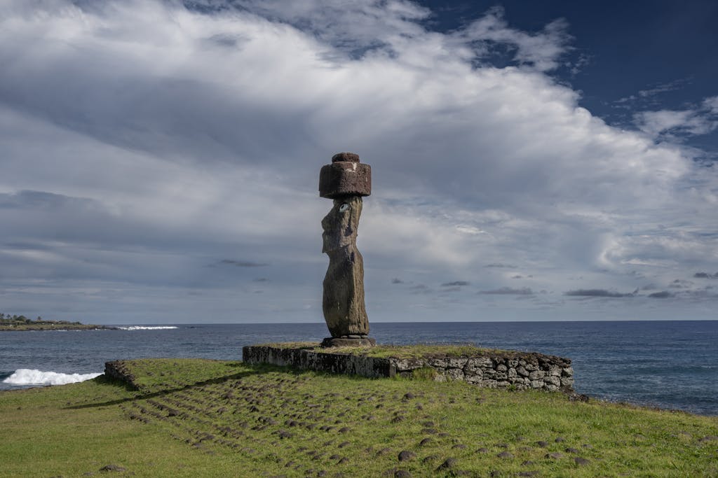 A stunning view of a Moai statue on Easter Island's coastline under a dramatic sky.