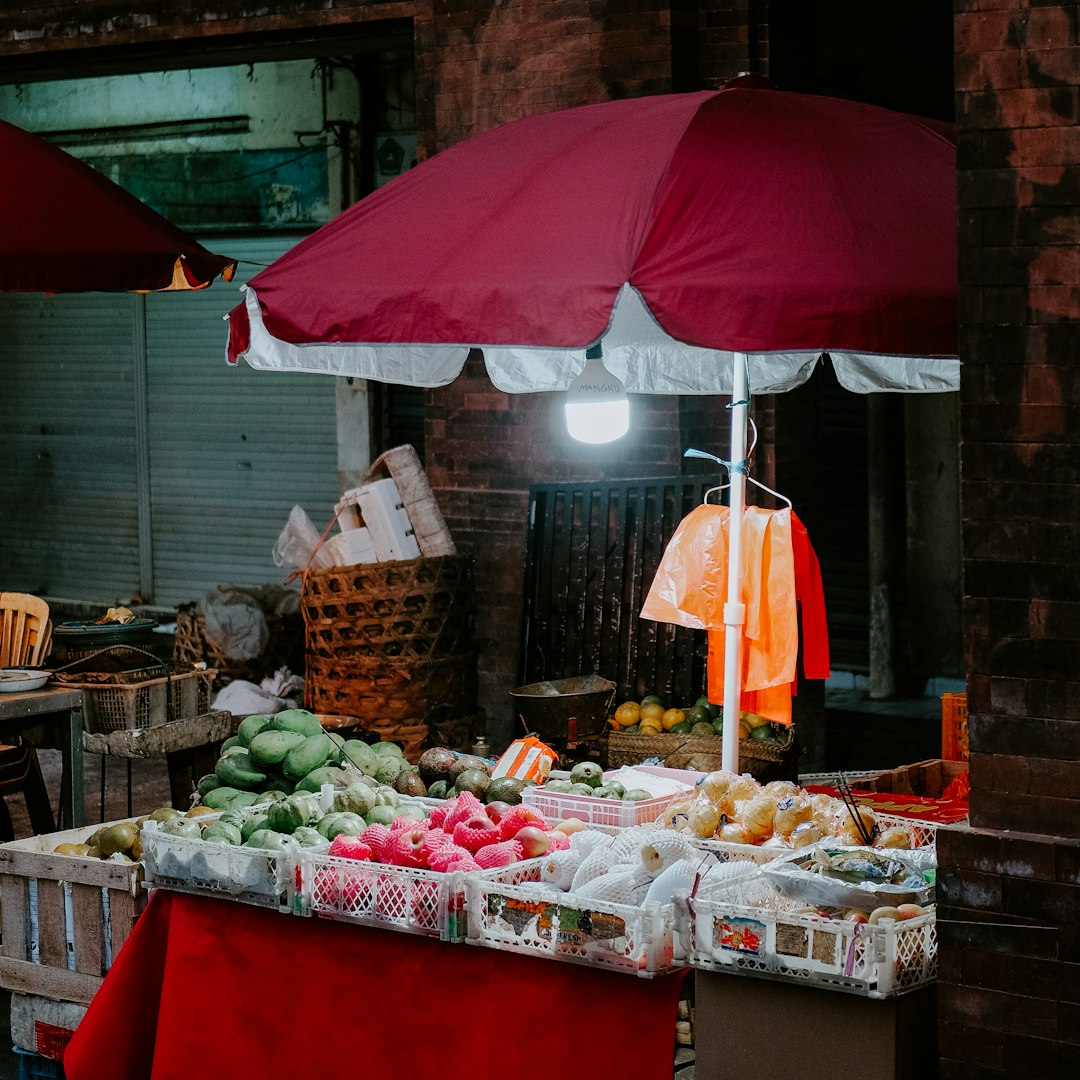 Puesto de fruta bajo una sombrilla roja en un mercado