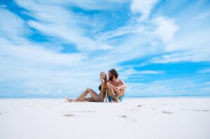 Pareja en la playa mirando a cámara durante su luna de miel